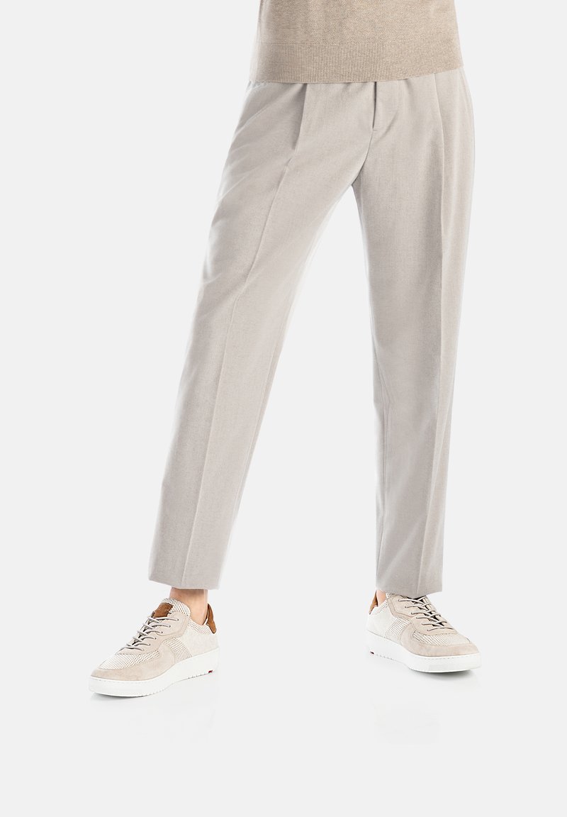 Helle graue, maßgeschneiderte Hose mit Falten, kombiniert mit beigen Sneakers, die Mesh- und Wildlederakzente aufweisen, vor einem weißen Hintergrund.