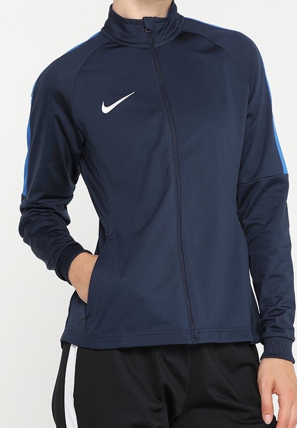 Veste de sport marine avec zip intégral, col haut et accents bleus sur les épaules. Dotée d'un logo Nike blanc sur la poitrine.
