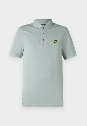 Lys grønn polo-shirt laget av bomull, med krage, tre knapper og en brodert gul logo på venstre bryst.