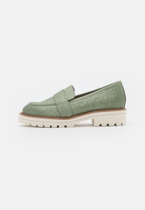 Mocassin vert texturé avec semelle blanche épaisse et garniture marron, style slip-on, vue de profil sur fond blanc.