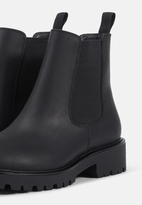 Melni ādas Čelsijas zābaki ar elastīgām sānu daļām, masīvu zoli un cilpiņām. Gluda tekstūra, vienkāršs dizains un izturīga konstrukcija.