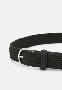 Cinturón de tela trenzada en verde oscuro, con una hebilla en tono plateado y un acento de cuero marrón. Textura suave con un diseño flexible y ajustable.