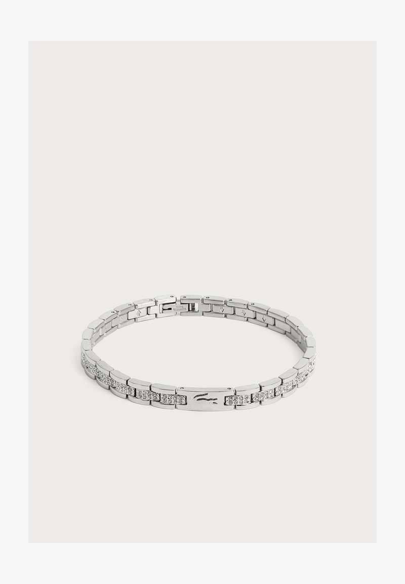 Bracelet chaîne en argent avec des maillons rectangulaires, certains sertis de petits cristaux et un fermoir avec un logo crocodile embossé.