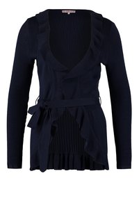 Námořnicky modrý žebrovaný cardigan s dlouhými rukávy, hlubokým výstřihem do V, volánkovými okraji a detailem na zavazování v pase. Jemná textura s rozšířeným spodním lemem.