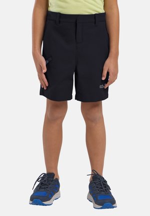 Schwarze Shorts aus leichtem Stoff, mit Seitentaschen und einem Logo. Kombiniert mit blauen und grauen Sportschuhen.