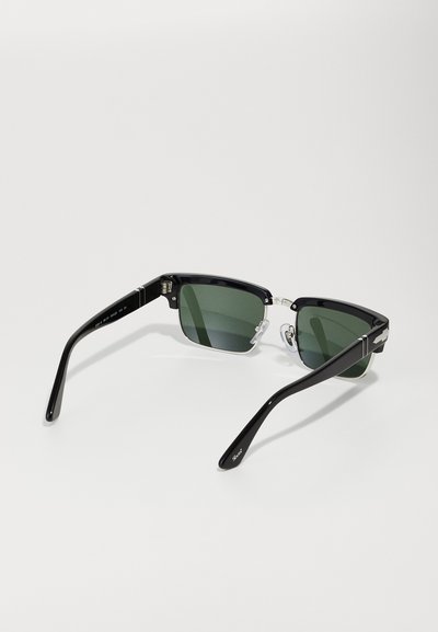 Ochelari de soare rectangulari negri cu lentile verzi, suporturi de nas transparente și brațe negre lucioase cu accente argintii. Textură mată, design modern.