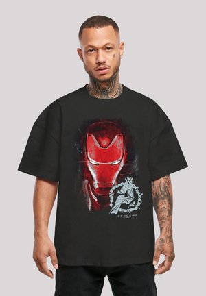 Mustan T-paidan, jossa on punainen Iron Man -graafinen kuvasto ja rikki mennyt Avengers-logo. Lyhyet, ylipitkät hihat ja puuvillakangasta.