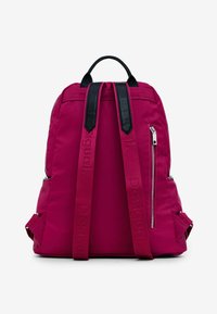 Sac à dos en nylon magenta avec des accents en cuir noir, sangles réglables, fermetures éclair latérales et une poignée supérieure. Présente un logo en relief sur les sangles.