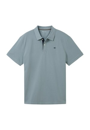Camisa polo azul claro con cuello clásico, tapeta de dos botones y un interior de cuello azul marino en contraste. Mangas cortas con costuras limpias.