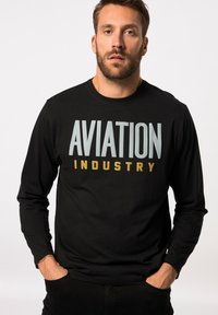 Schwarzes Langarm-T-Shirt mit "AVIATION" in Hellblau und "INDUSTRY" in Gold. Der Stoff wirkt glatt und dehnbar.