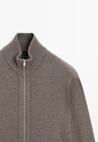 Grauer Strickpullover mit Reißverschluss und hohem, geripptem Kragen, verfügt über einen silbernen Reißverschluss und eine strukturierte Stoffoberfläche. Glatte Oberfläche mit enger Passform.