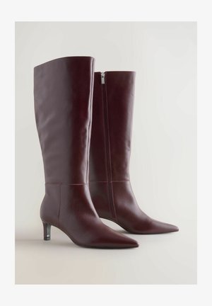 Burgundske usnjene škornje do kolen s koničastim nosom, dekorativnim šivanjem in stranskim zadrgo. Imajo nizek, ozek peto.