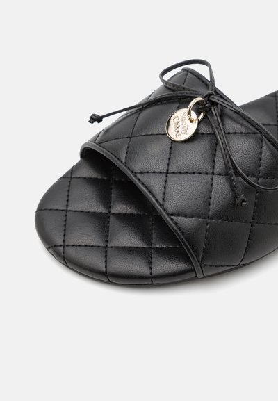 Sandal cu talpă slide, capitonat, de culoare neagră, cu un superior din piele moale, design cu vârf deschis și o fundă decorativă cu o etichetă mică branduită.