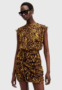 Robe à imprimé léopard avec des manches volantées, présentant une silhouette ajustée et une texture froncée. Principalement jaune avec des accents noirs et rouges.