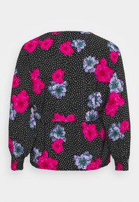 Blouse noire à manches longues avec des pois, ornée de motifs floraux vibrants en rose et bleu. Elle présente une coupe décontractée et des poignets élastiqués.