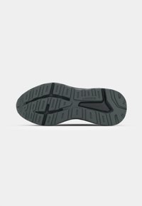 Sole di scarpa in gomma nera con grip a motivo, scanalature profonde, un logo al centro e una sezione liscia attorno al tallone.