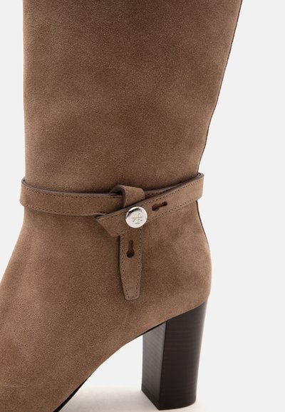 Botte marron en daim à talon haut avec sangle enveloppante et détail de bouton argenté sur le côté, avec talon bloc.