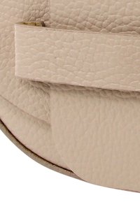 Ronde leren tas in zacht beige met een gestructureerde afwerking, voorzien van een klepsluiting en gelaagde designelementen. Minimalistische hardware accenten.