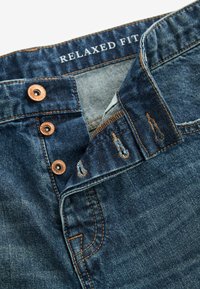 Jeans din denim cu croi lejer, de culoare albastru închis, cu nasturi cupru, talie cusută și detalii de cusătură vizibile.