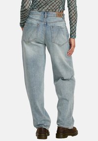 Lyseblå denimjeans med løs passform, høy midje, baklommer og et brunt merke ved livlinjen.
