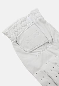 Valkoinen nahkakäsine, jossa on rei'ityksiä hengittävyyden lisäämiseksi, kudottu hihnadesign ja kohokuvioitu logo-patch, jossa lukee "BOSS."