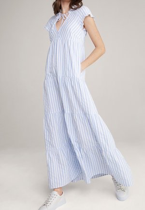 Długa sukienka maxi w niebiesko-białe paski, z krótkimi falbanianymi rękawami, dekoltem w serek, zawiązywana na kokardę, z kieszeniami i wielowarstwowym dołem. Noszona z białymi trampkami.