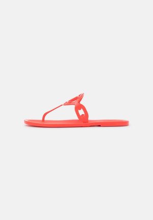 Rode platte teenslipper met een cirkelvormig uitsnijdingsdesign op het bandje, zijaanzicht op een witte achtergrond.