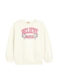 Sweatshirt blanc à col rond, à manches longues. Sur le devant, un graphique en texte rose indique "CROIS EN MAGIQUE" avec des illustrations de licornes. Texture douce.