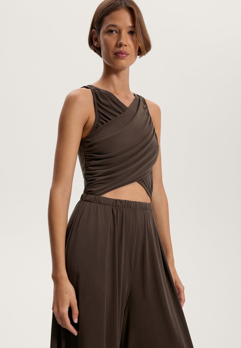 Braunes ärmelloses Oberteil mit Raffung und überkreuztem Vorderteil, kombiniert mit passenden, weiten Hosen mit elastischem Bund.
