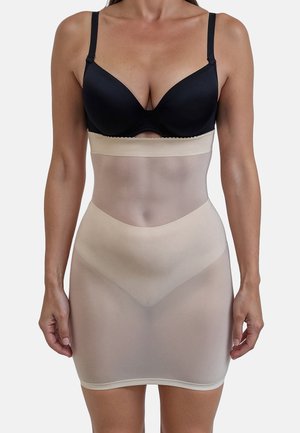Beige shapewear slip van doorzichtig materiaal, met een elastische tailleband en naadloos ontwerp, dat tot halverwege de dij reikt.
