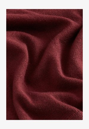 Tissu tricoté bordeaux avec une texture douce, présentant une surface lisse et légèrement extensible ainsi que de subtiles variations de couleur et de tissage.