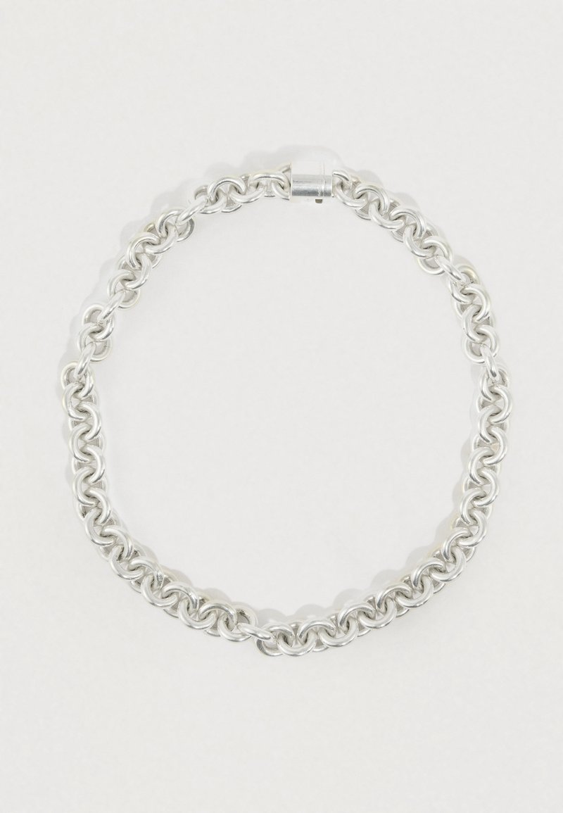 Sølvkædearmbånd med sammenlåste runde led, med en glat tekstur og en metal lås for sikker fastgørelse.
