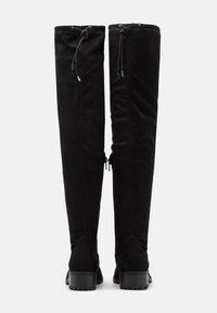Botas negras de ante por encima de la rodilla, con cordones ajustables en la parte superior y suelas de goma gruesa con tracción.