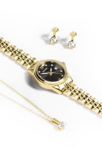 Montre dorée avec un cadran noir et des marqueurs en pierre précieuse, accompagnée de boucles d'oreilles et d'un collier en or, ornés de pierres claires et de chaînes délicates.