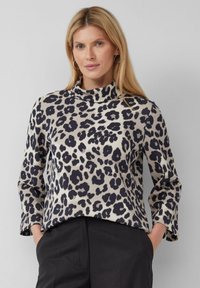Top con stampa leopardata e colletto alto, caratterizzato da uno sfondo crema e macchie nere. Maniche lunghe e vestibilità comoda. Tessuto morbido e liscio.