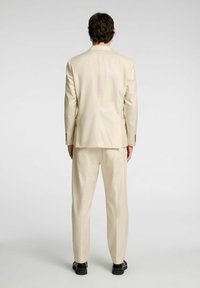 Beżowy garnitur składający się z dopasowanej marynarki i spodni, charakteryzujący się gładką teksturą oraz prostym, eleganckim wzornictwem, widok z tyłu.