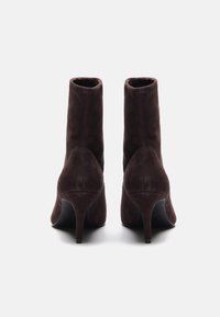 Mørkebrune mocka ankelstøvler med en tettsittende design, høye stilettohæler og en jevn tekstur. Rene linjer og ingen synlig maskinvare.
