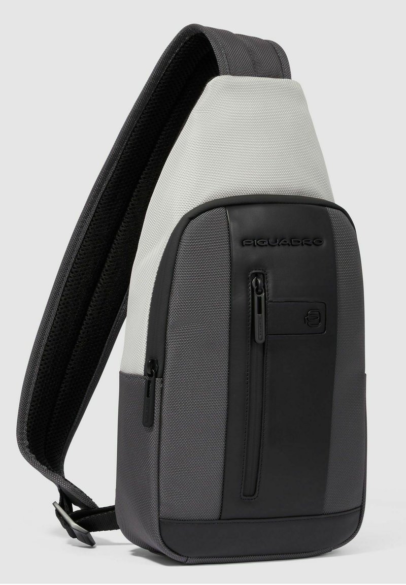 Zaino a tracolla con spallacci imbottiti neri e grigi, tessuto grigio strutturato, pannello frontale nero, tasca verticale con zip e design con logo.