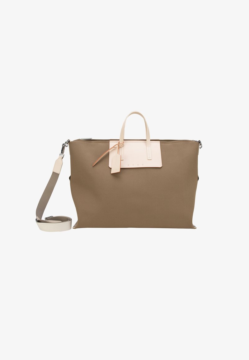 Grand sac fourre-tout taupe avec poignées crème, bandoulière détachable et une petite étiquette à bagages attachée sur fond blanc.