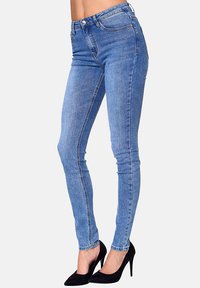 Jeans ajustados de mezclilla de color azul, con cintura alta y bolsillos frontales, combinados con zapatos de tacón alto negros.