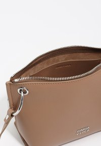 Brązowa torba na ramię wykonana ze skóry naturalnej, z zamkiem błyskawicznym i elementami metalowymi w srebrnym kolorze. Wnętrze ma gładką powierzchnię; na zewnętrznej stronie znajduje się tłoczone logo.