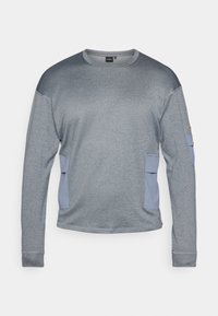 Gray athletic long-sleeve shirt with a textured finish, featuring light blue side pockets and a round neckline. No visible logos.
