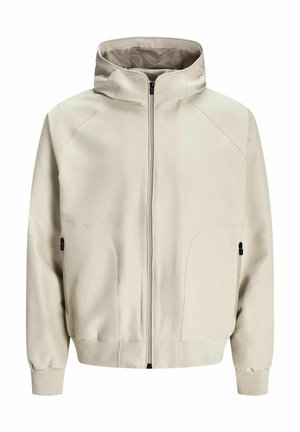 Ljust beige huva med dragkedja, sidfickor och ribbade muddar. Slät tyg med matt finish och subtila sömnadsdetaljer.