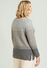 Grijze gebreide trui met een verloopontwerp, voorzien van zilveren accenten en zijsplitten. De textuur is zacht, met een losse pasvorm.