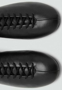 Czarne skórzane buty, zaokrąglony czubek, o teksturowanym wykończeniu. Posiadają krzyżowe sznurowanie na wierzchu, co tworzy elegancki design.