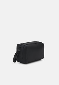 Trousse de toilette rectangulaire noire en cuir lisse, dotée d'une fermeture zippée sur le dessus et d'une poignée latérale pour un transport facile.