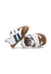 Zapatos infantiles blancos y marrones con dos rayas azules, correas de velcro, un acabado de gamuza texturizada y suela de goma.