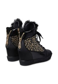 Sneaker alte nere con zeppa, texture lucida, impreziosite da paillettes dorate, bordo in pelliccia sintetica e doppia cerniera ai lati.
