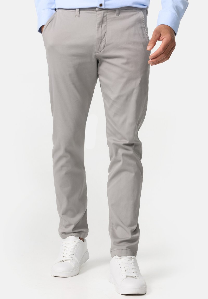 Chino gris clair avec une coupe slim, fabriqué en tissu mélange de coton. Dispose de poches latérales et d'une texture lisse. Associé à des baskets blanches.