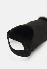Sort stofpose med en struktureret overflade, åben foroven, med en sikringsrem på siden for ekstra bekvemmelighed.